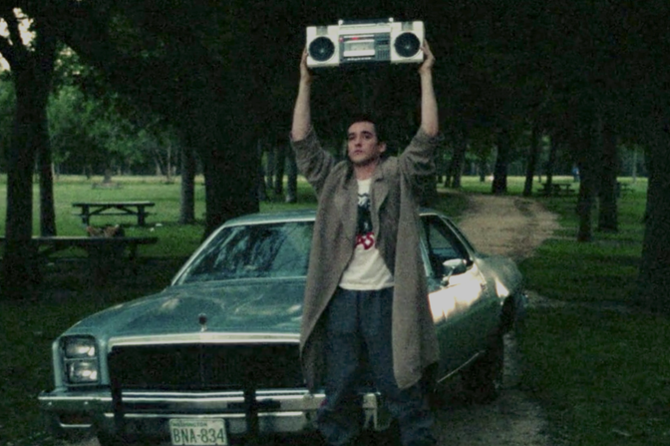 john cusack holds a boombox up in front of an &#x27;80s car