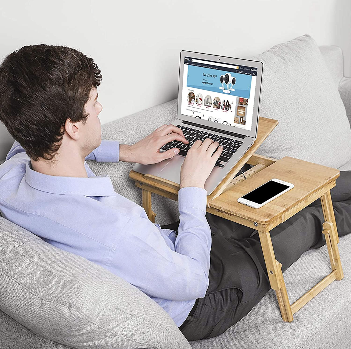 A person is using a caddy to work while lounging on a sofa