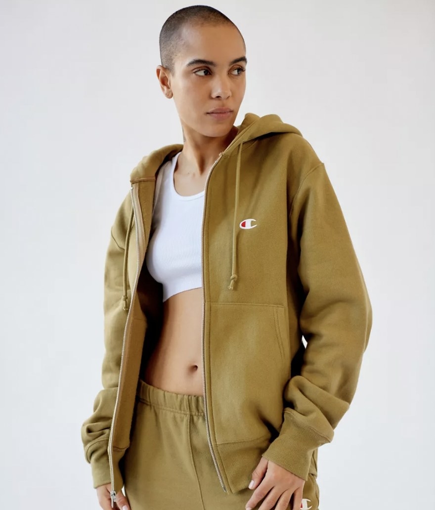 A person with a shaved head wearing a camo green hoodie