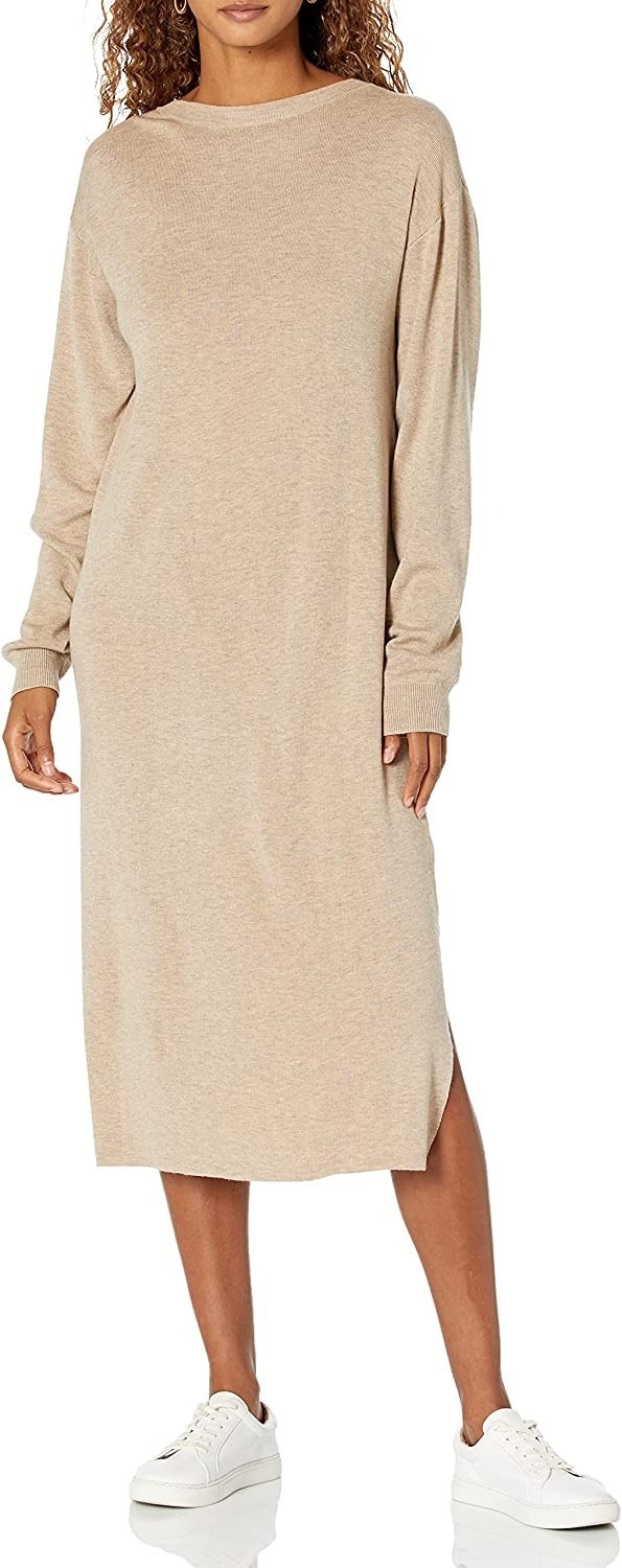 model wearing the beige long-sleeve sweater dress with white sneakers