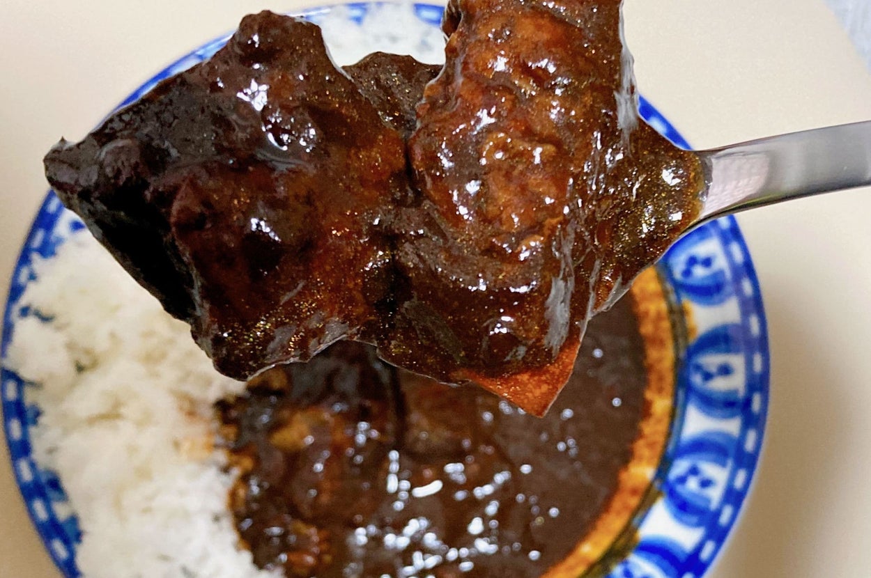 スプーンで持ち上げられたカレーとご飯の一部が見える皿。