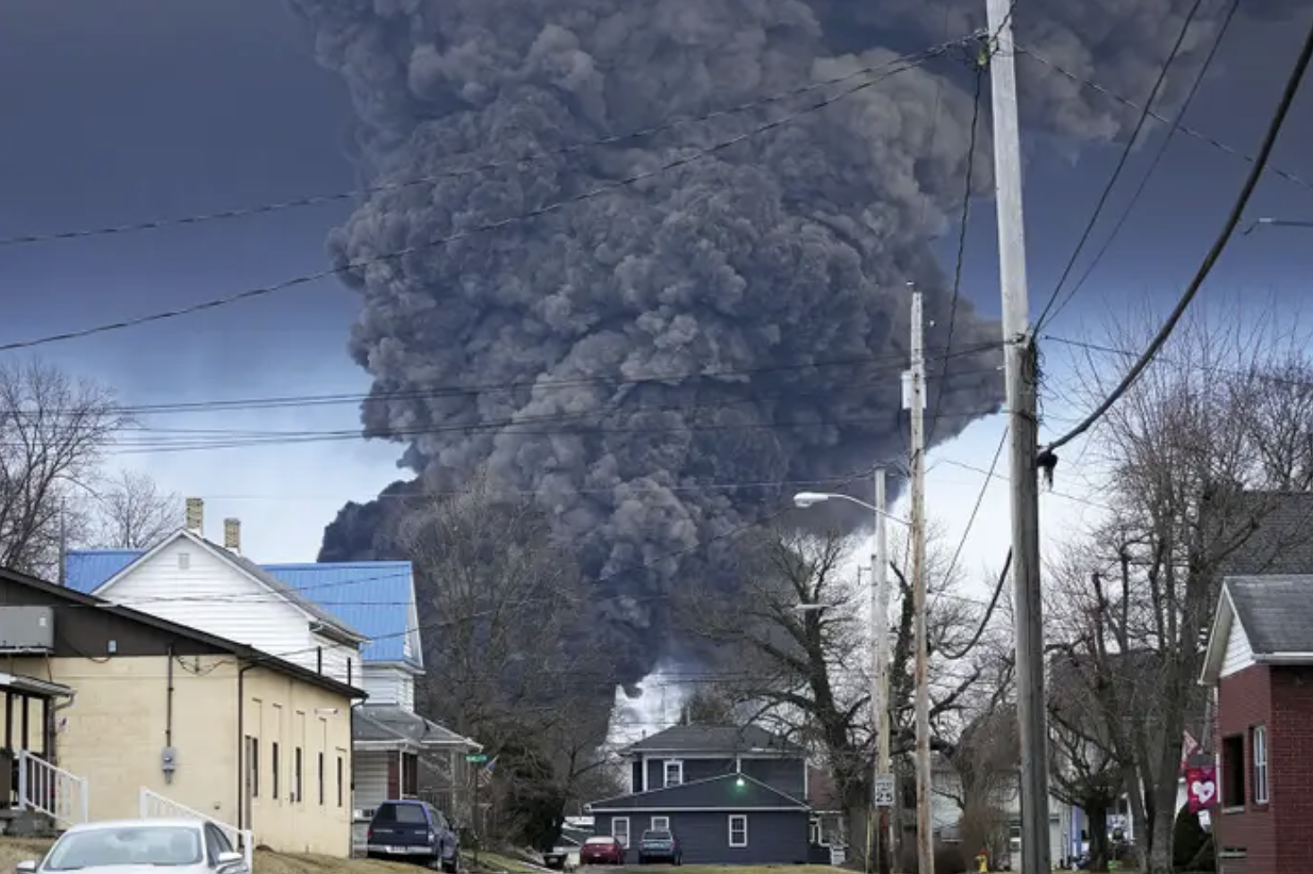 above a suburban neighborhood, a huge plume of black smoke rises