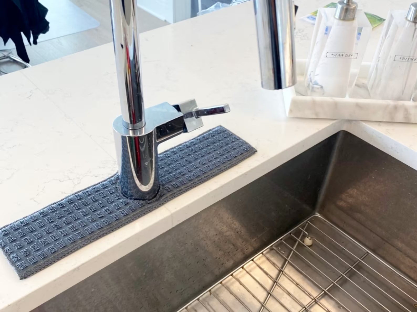 Absorbent gray rectangle of fabric placed around the base of a kitchen sink faucet