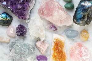 a group of crystals, including amethyst, quartz rose, labradorite, citrine, celestine, pierre de lune, aventurine, rhodonite, and quartz.
