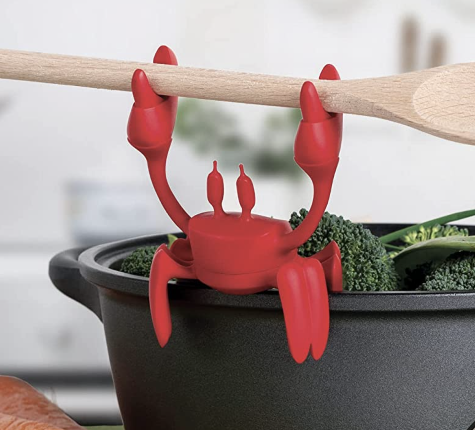 the crab spoon rest on the side of a pot holding a wooden spoon