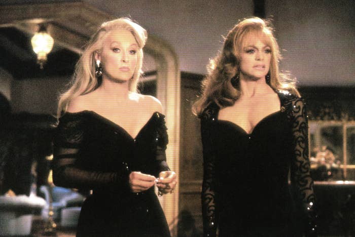 Meryl Streep and Goldie Hawn stand next to each other wearing similar shimmery, dark gowns as Madeline and Helen