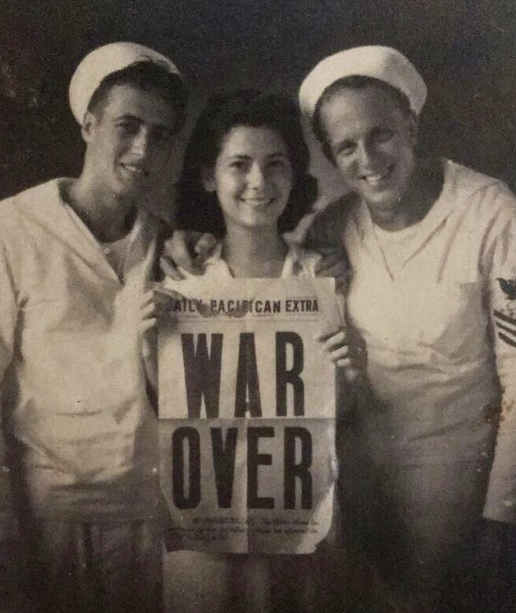 A woman holding a &quot;War Over&quot; newspaper next to two soldiers