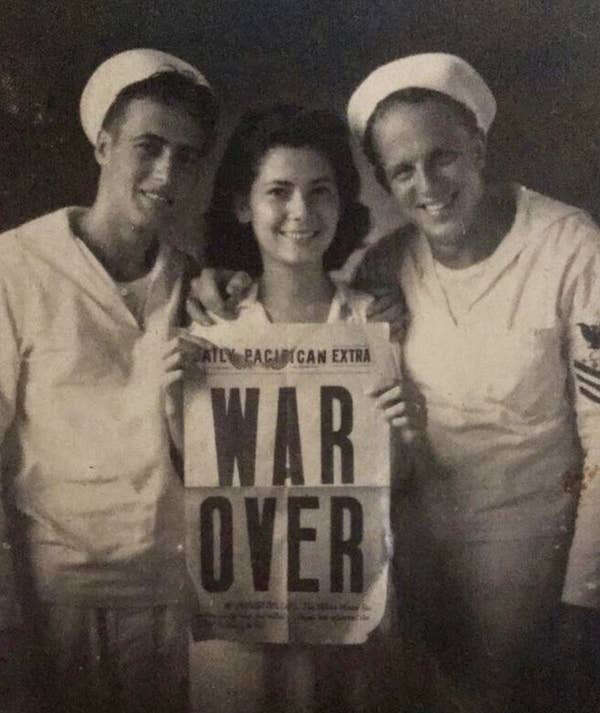 A woman holding a &quot;War Over&quot; newspaper next to two soldiers