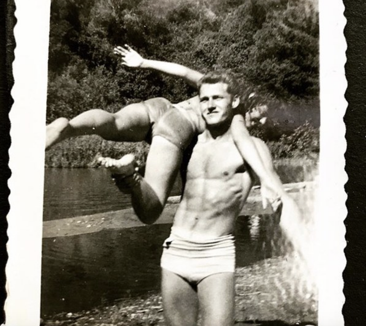A young man carrying another man in a bathing suit