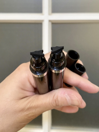 reviewer holds two stamps, which each have a slightly curved end for adding a winged eye to black eyeliner