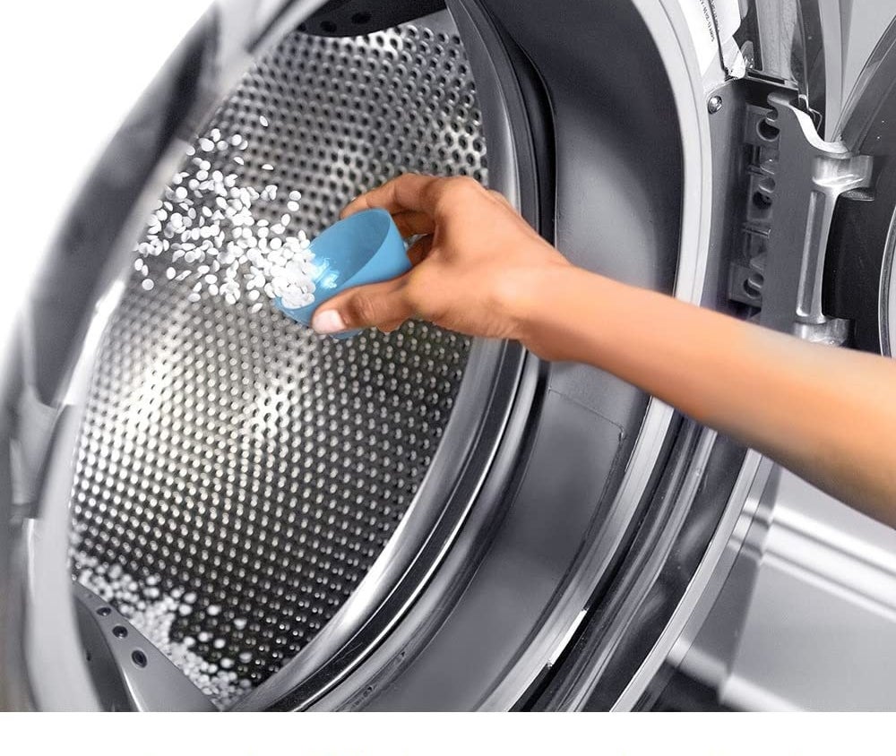 person dumping the scent boosters into the laundry drum