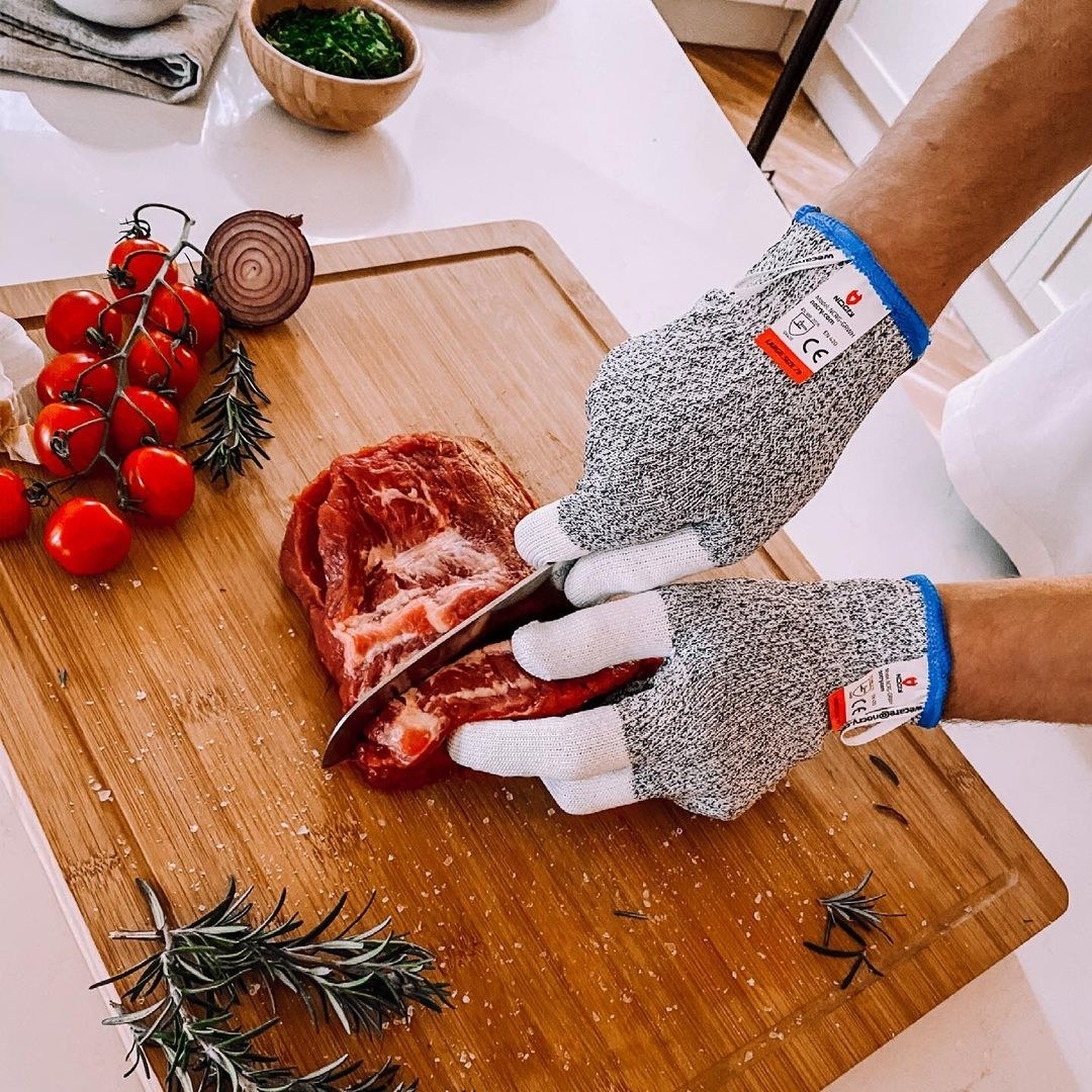 A person cutting into a piece of meat while wearing the gloves