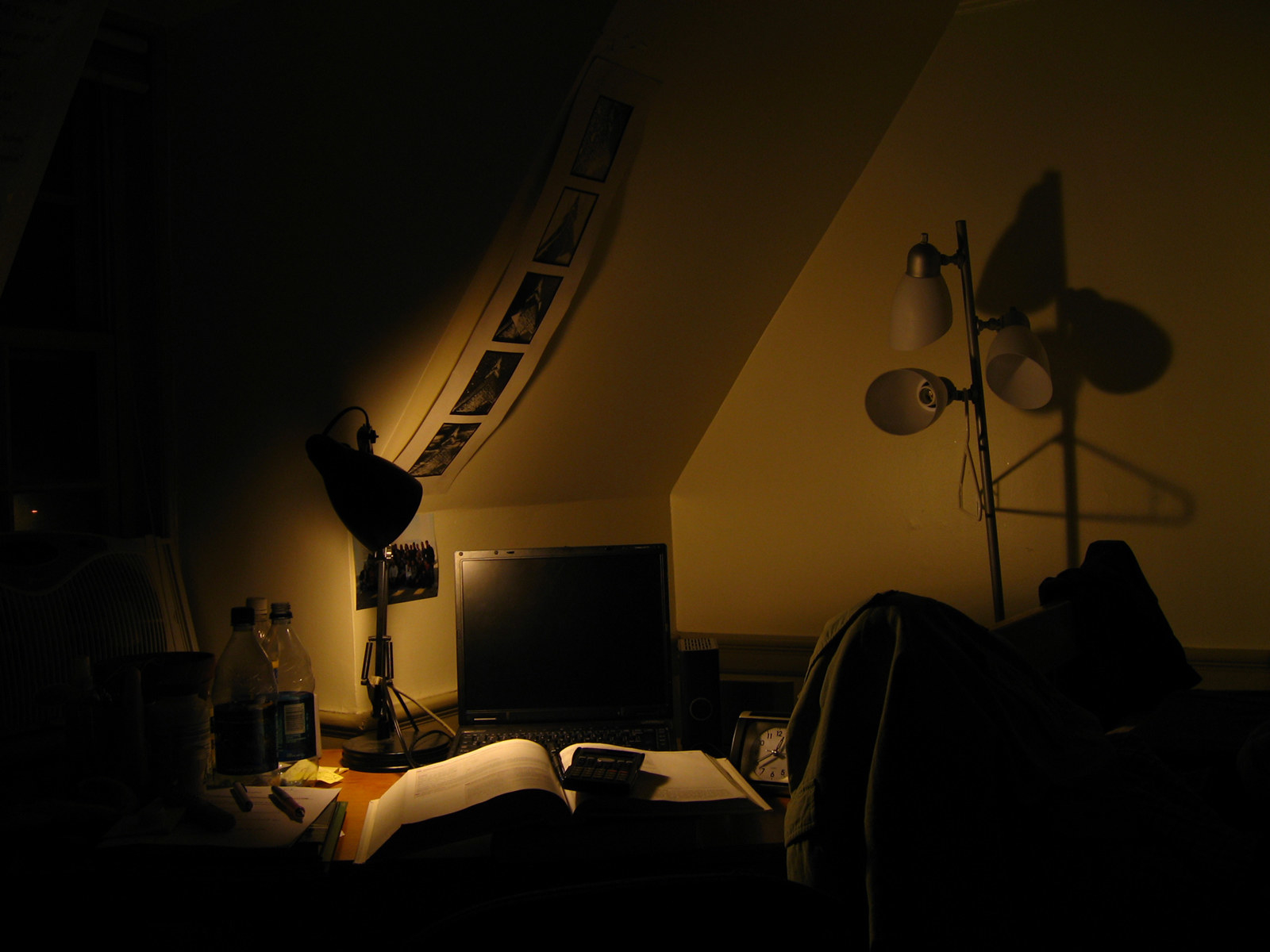 A study desk with computer, textbook, calculator, and a lone lamp in the evening.