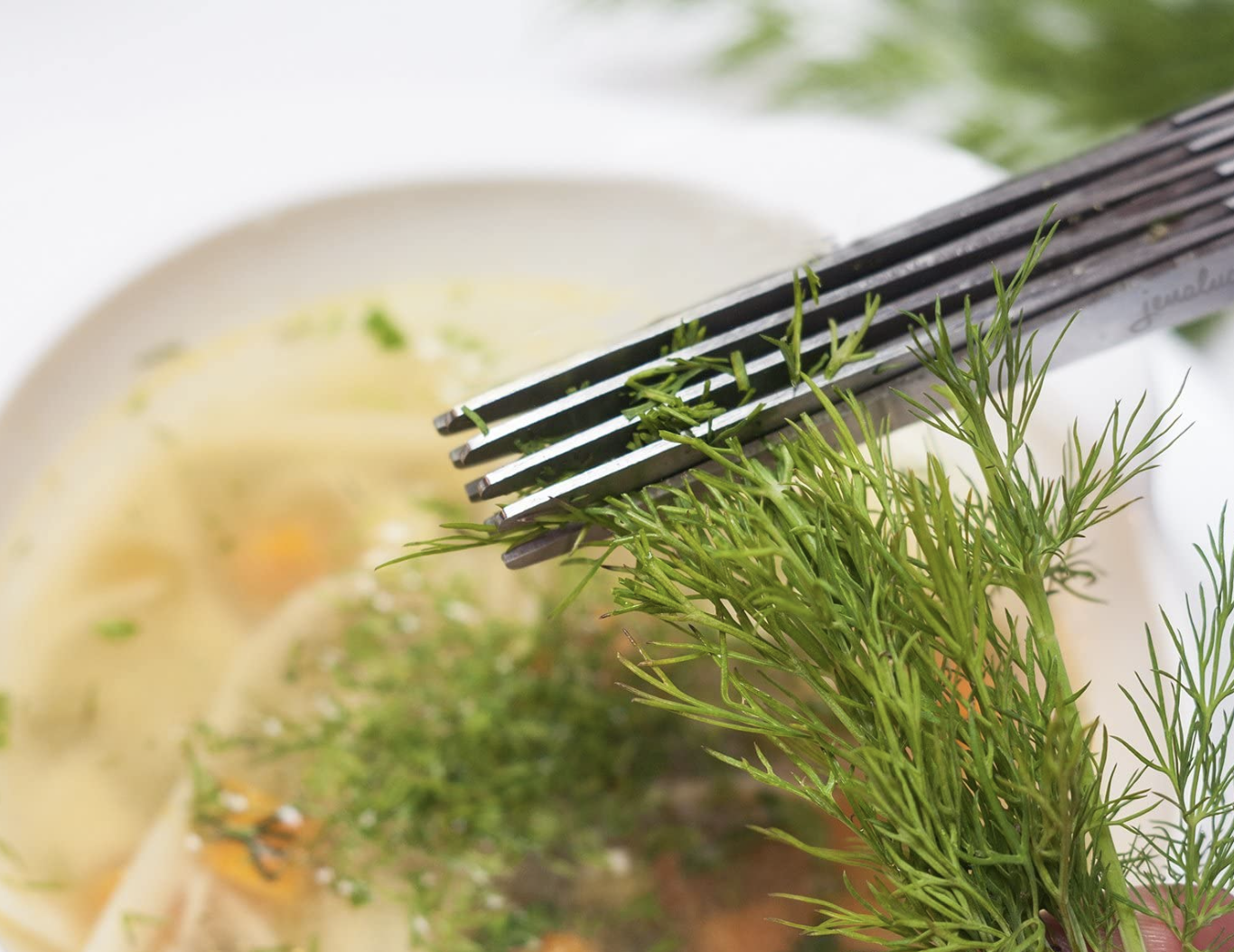 the scissors being used to clip herbs directly onto food in a plate
