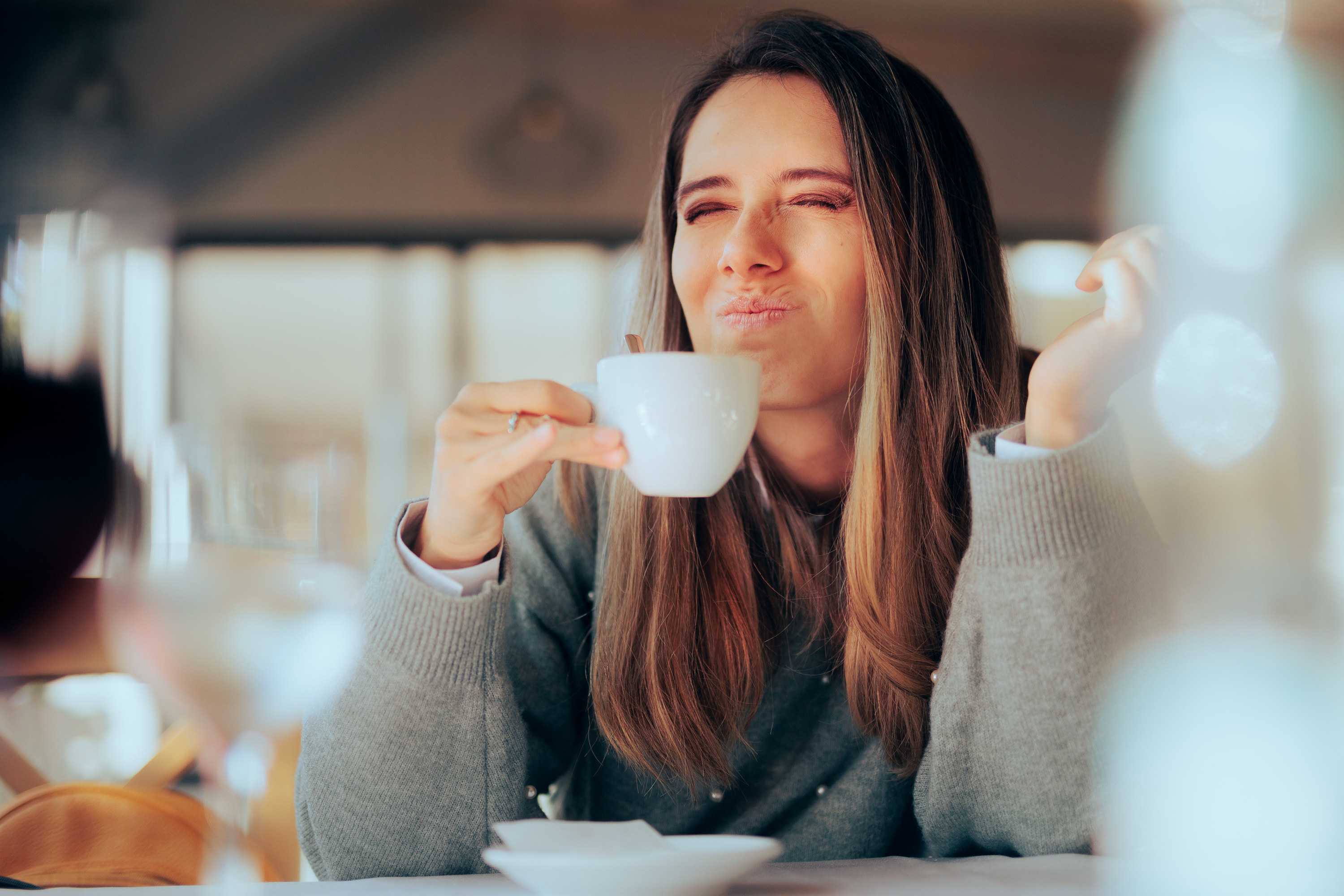 woman making a face after sipping a bitter coffee