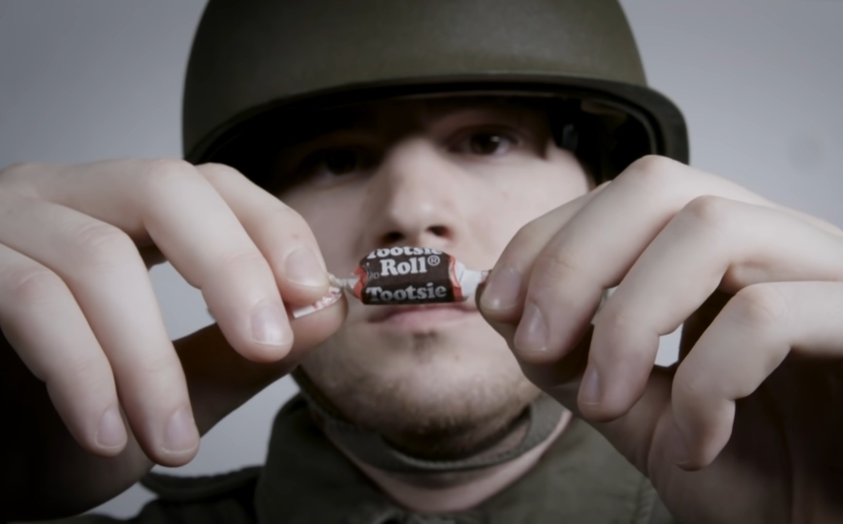 A soldier unwraps a Tootsie Roll