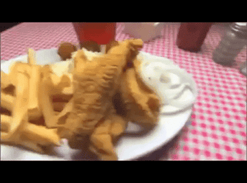 A plate of fish and chips is slid across a table