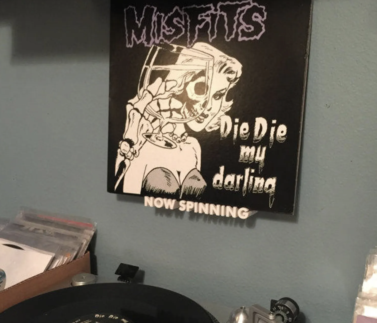 the vinyl shelf with white lettering that reads now spinning and holding a vinyl