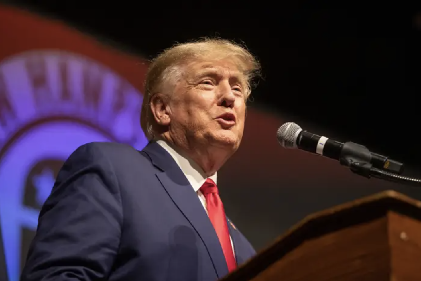 donald trump in a suit and red tie standing at a podium