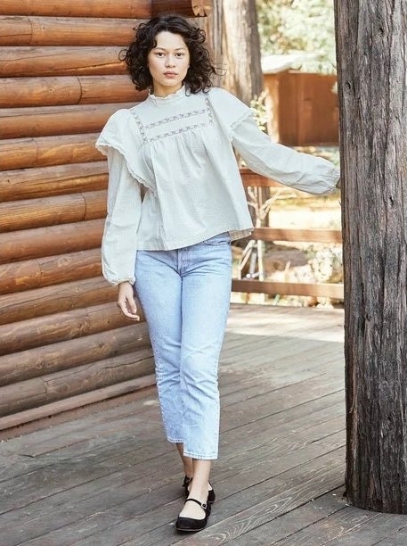 Model wearing white top with light wash jeans and black shoes