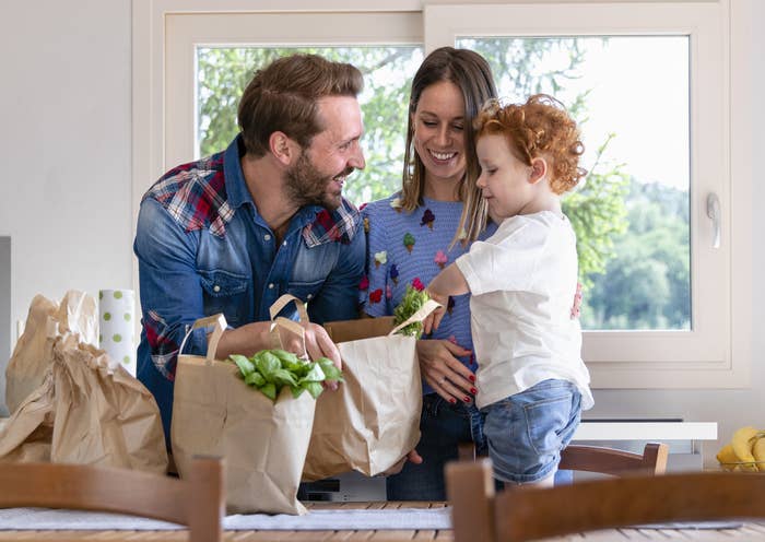 Dad and mom unload groceries with son onto table