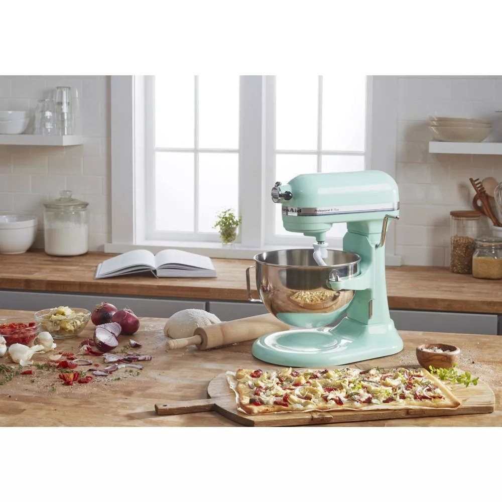 Mint green kitchenaid stand mixer in front of flatbread and ingredients on table