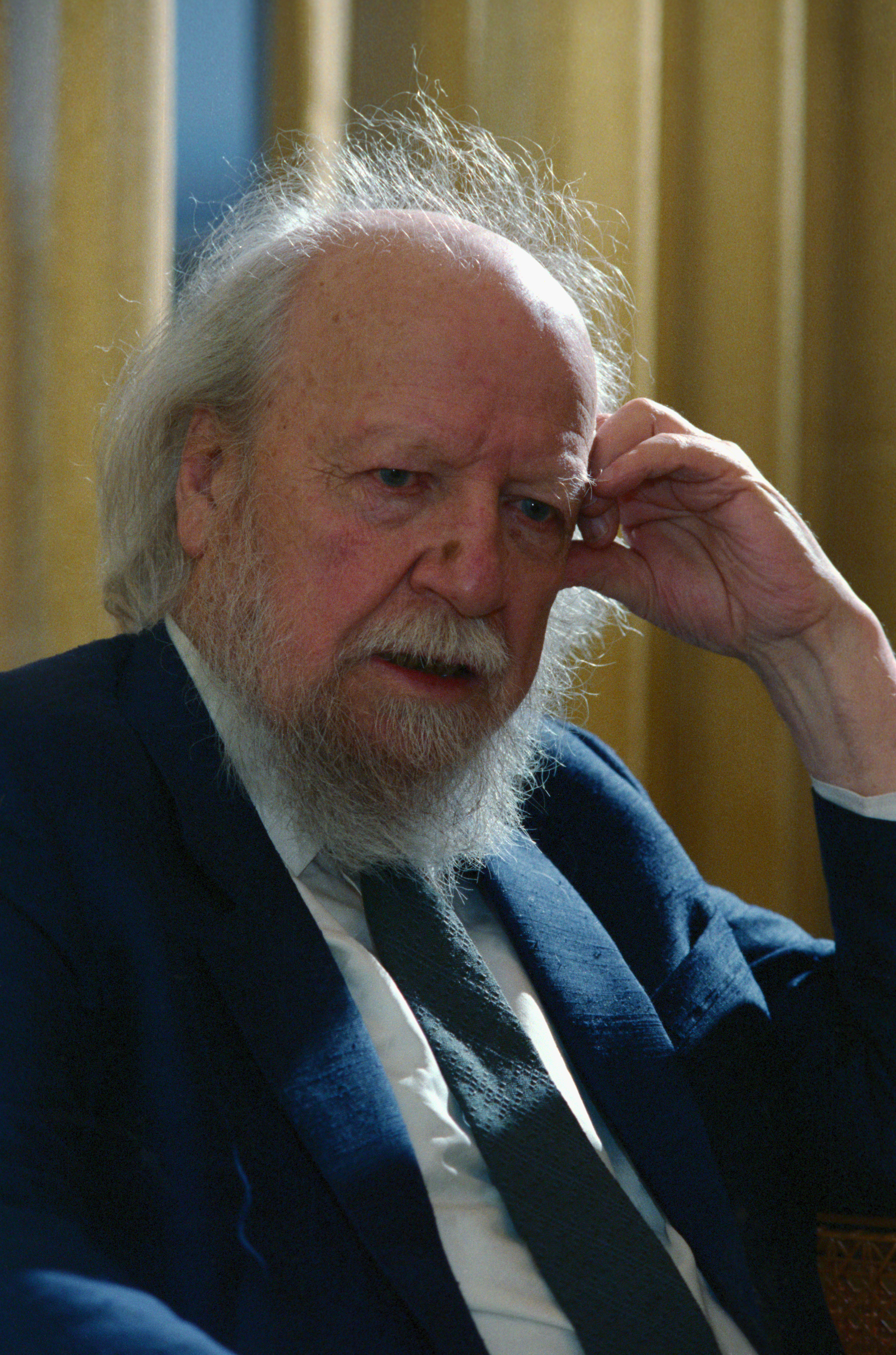 William Golding sitting with his hand touching his head
