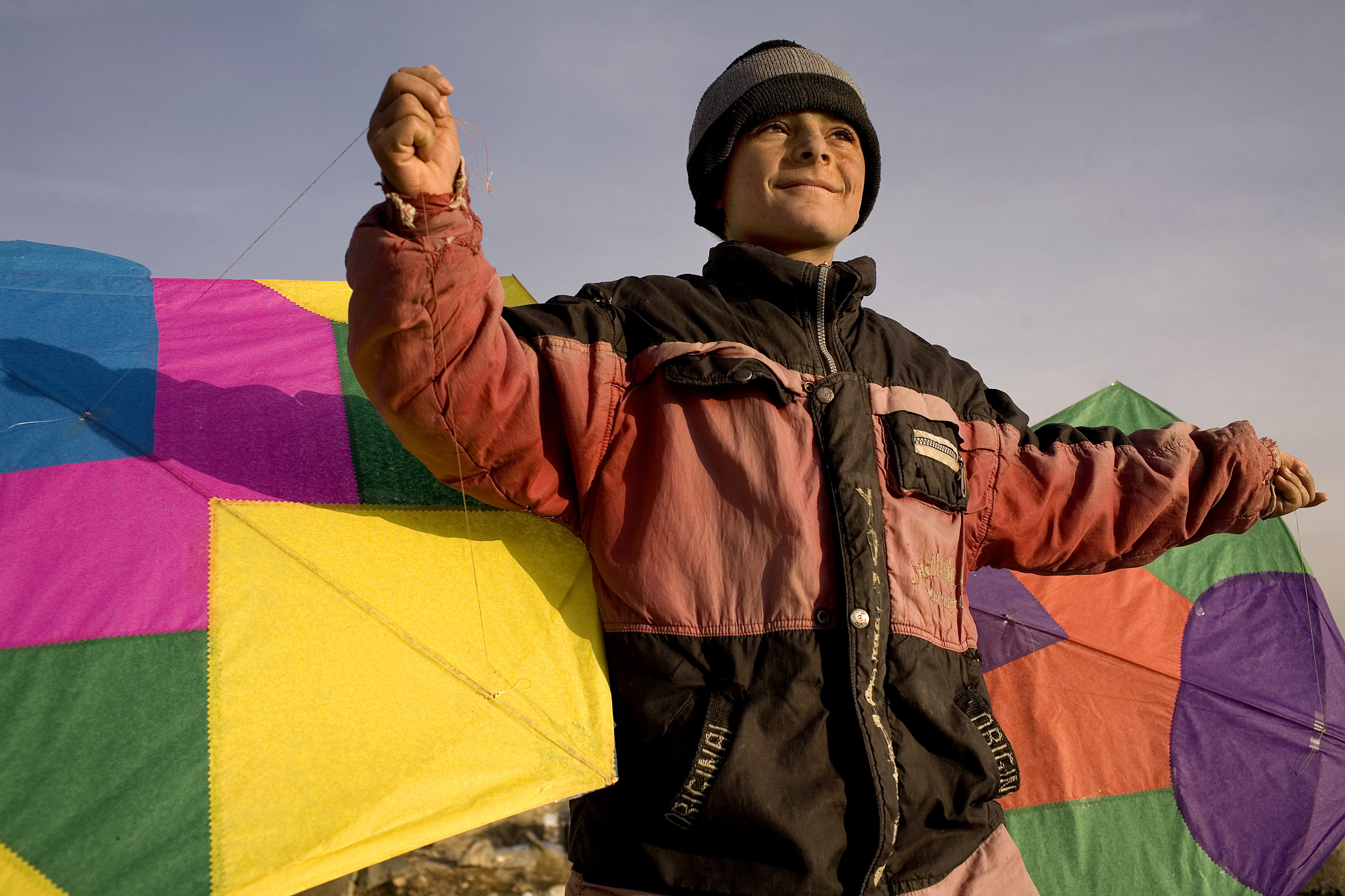 A young boy holding two kites