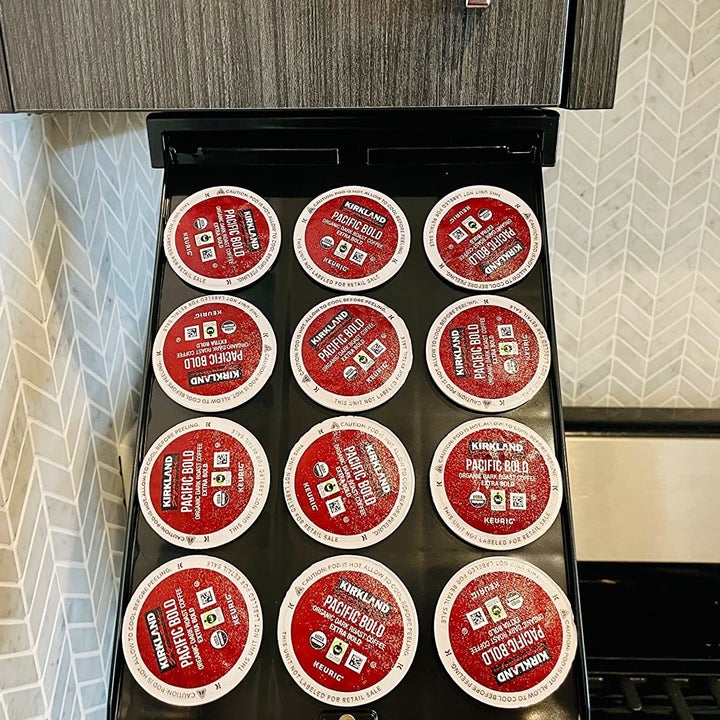 reviewer showing the hidden storage stray under a cabinet holding K-cups