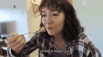 Woman holding a fork in front of her face and saying &quot;food is magic&quot;