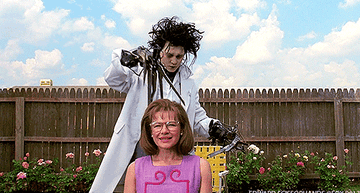 Edward Scissorhands cutting a woman&#x27;s hair outside