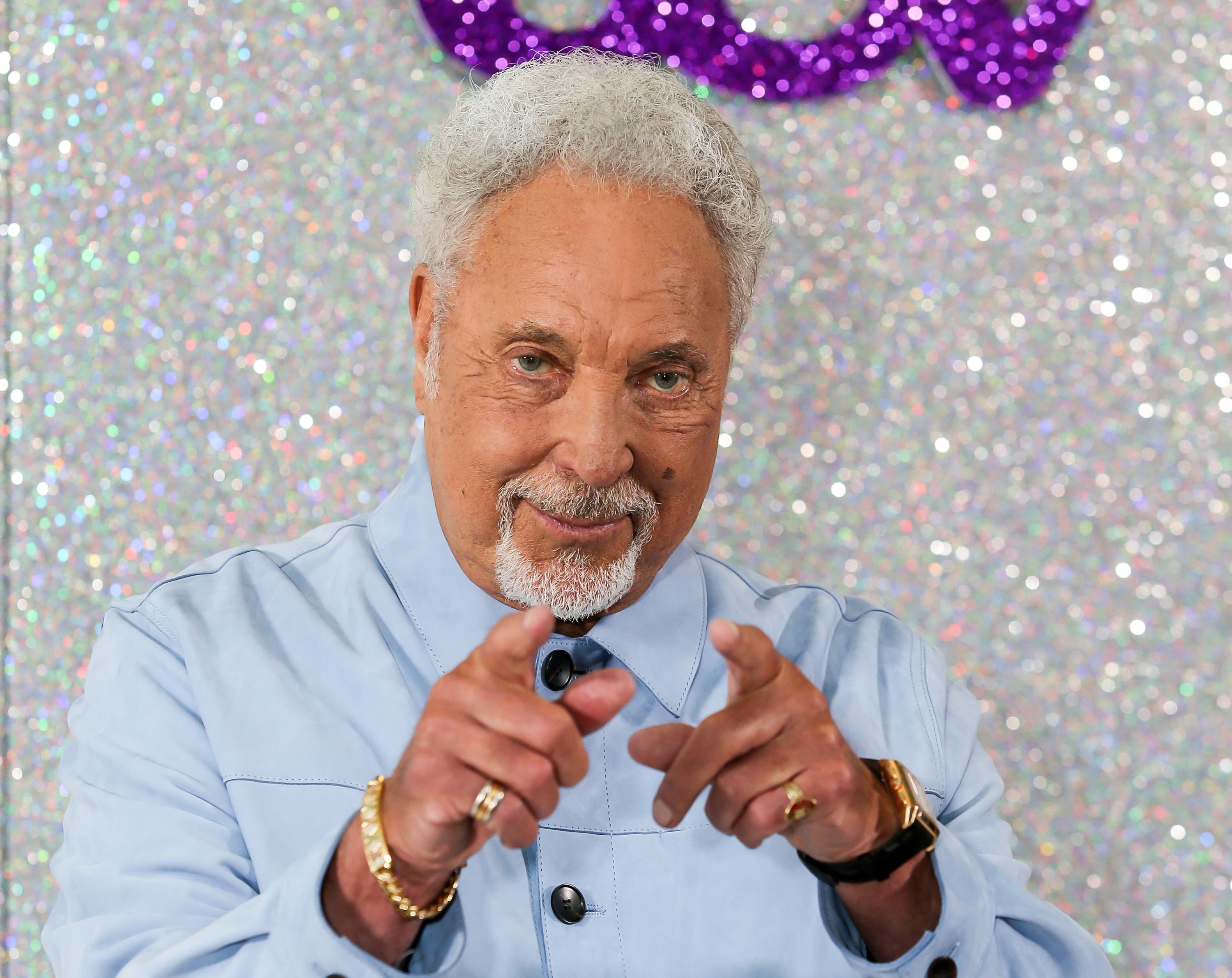 tom jones pointing in a light blue shirt