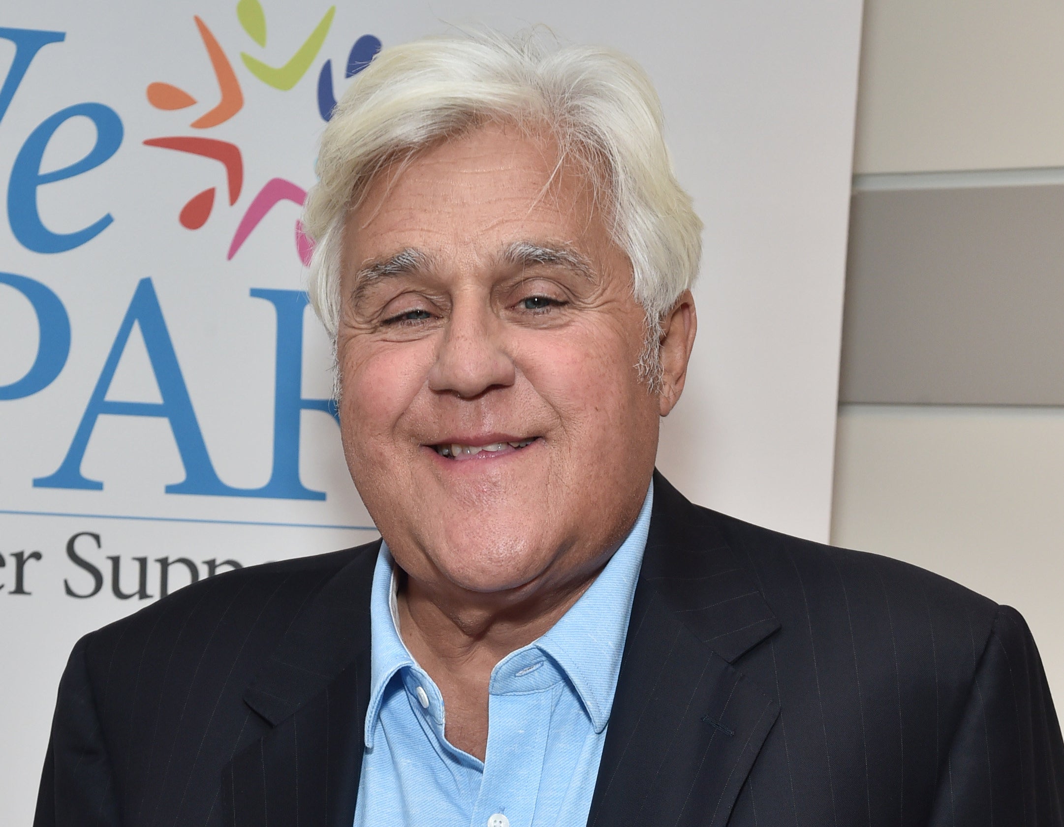 jay leno in a light blue shirt and striped blazer