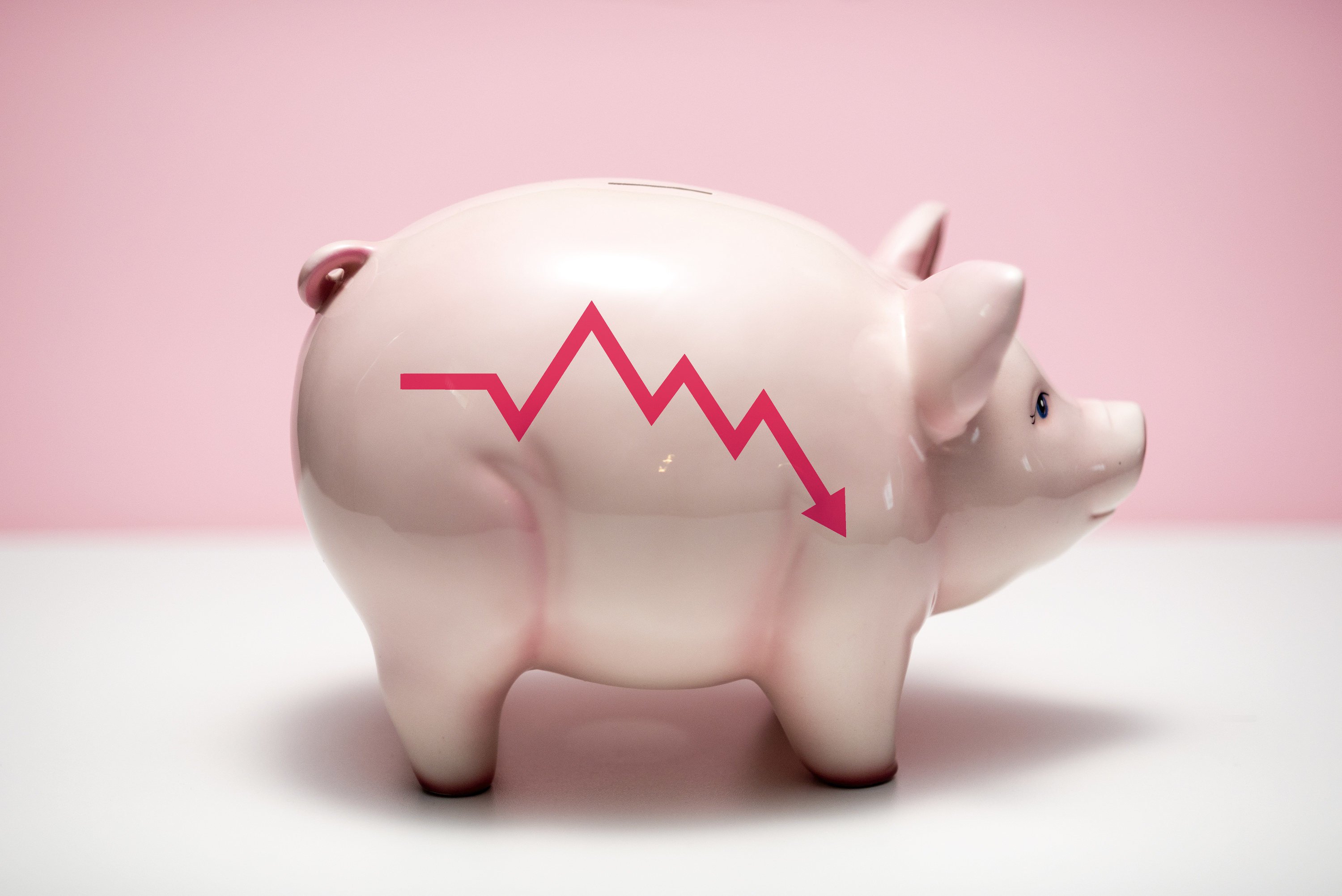 Piggy bank with a downward stock trend arrow on it