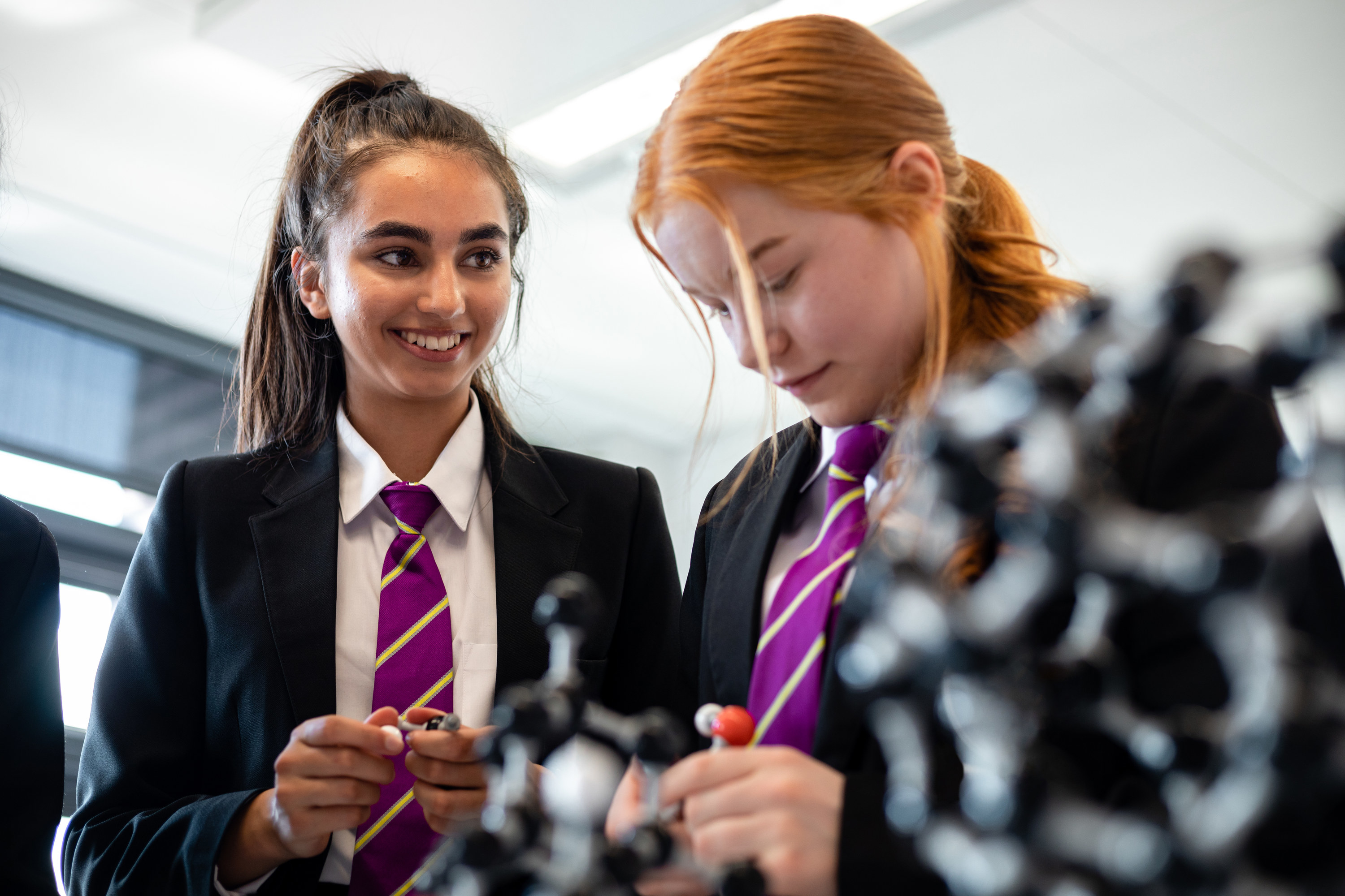 two teenage girls in uniforms working with science manipulatives