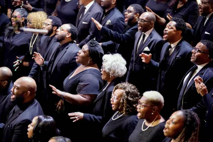 A choir of people singing in black funeral formalwear