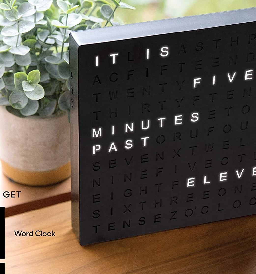 The clock in front of a plant on a wood table