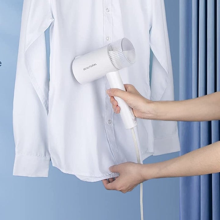 someone using the steamer on a shirt