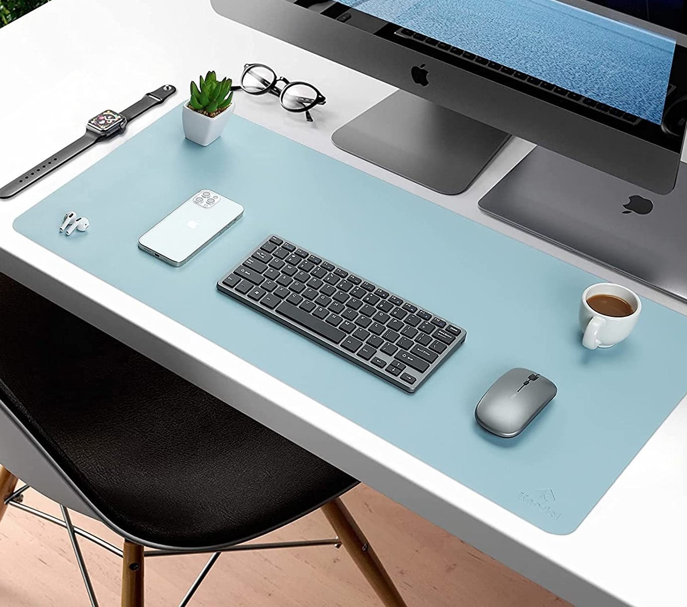 The desk mat in front of a monitor with a keyboard, mouse, plant, and phone on it