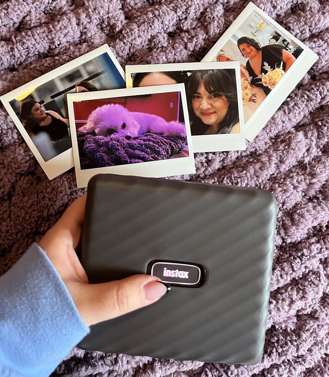 Bianca holding the photo printer above a few photo's she has printed