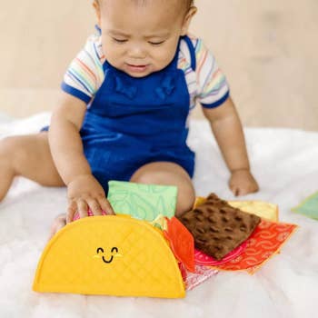 Baby exemplary playing with happy-faced taco toy