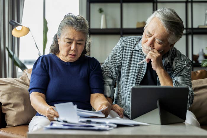 older asian couple doing paperwork from the couch