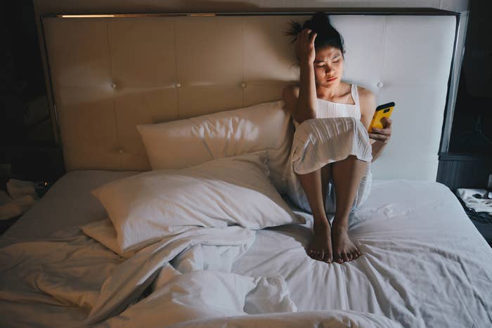A woman in bed and on her phone