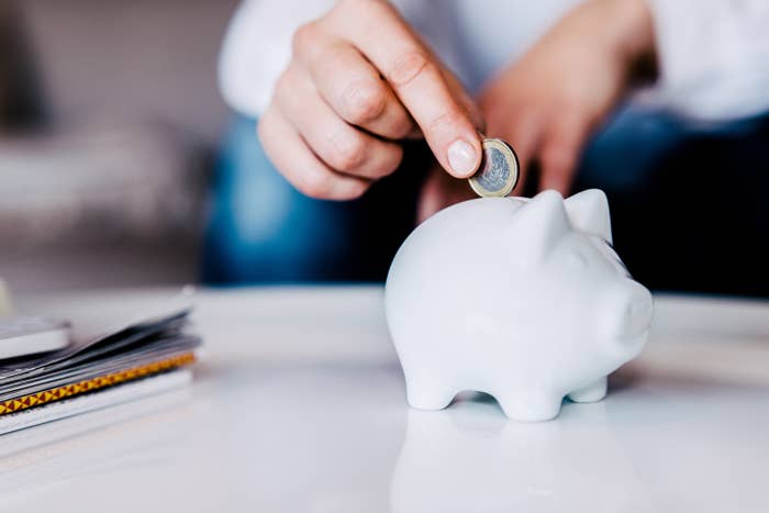 a person putting a coin in a piggy bank