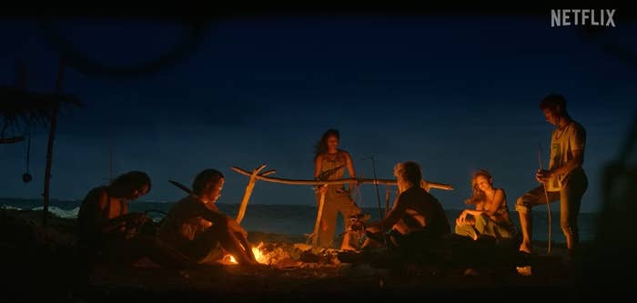 The entire group sat near a fire on the beach