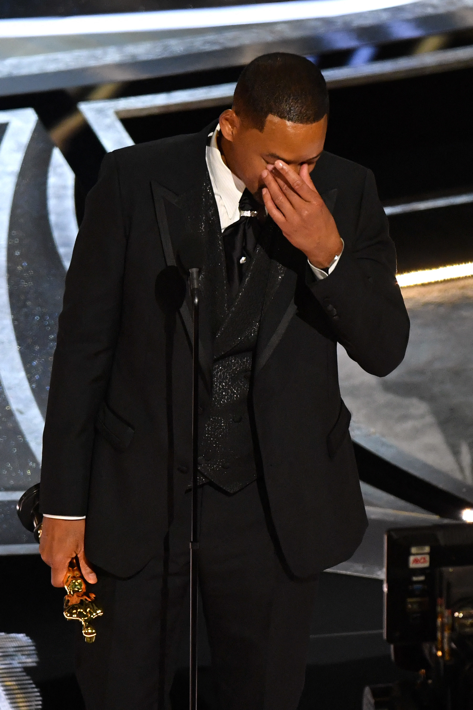 Will onstage covering his face with his hand and holding his Oscar during his acceptance speech