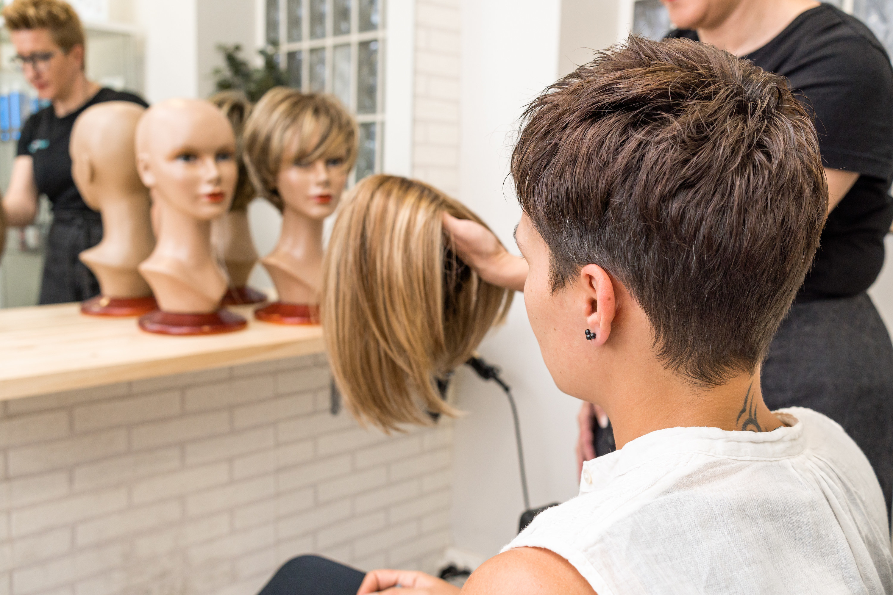 A stylist holding a wig in front of a client