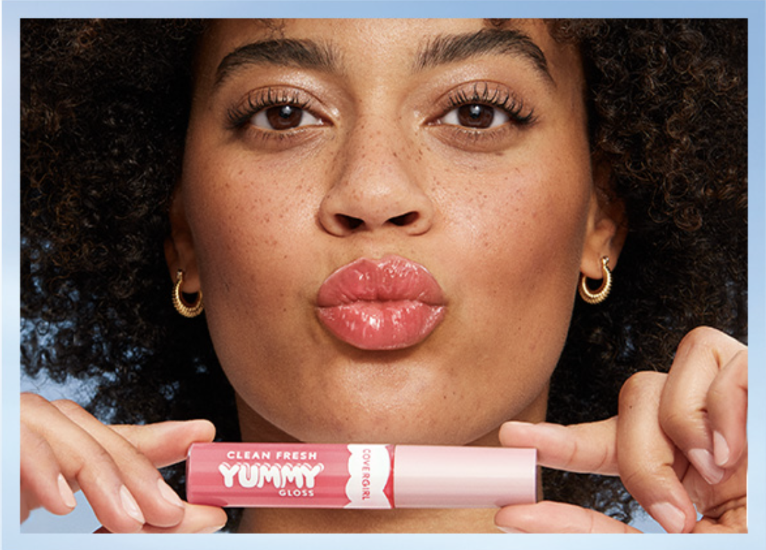 a model holding up a tube of the gloss while pouting their lips