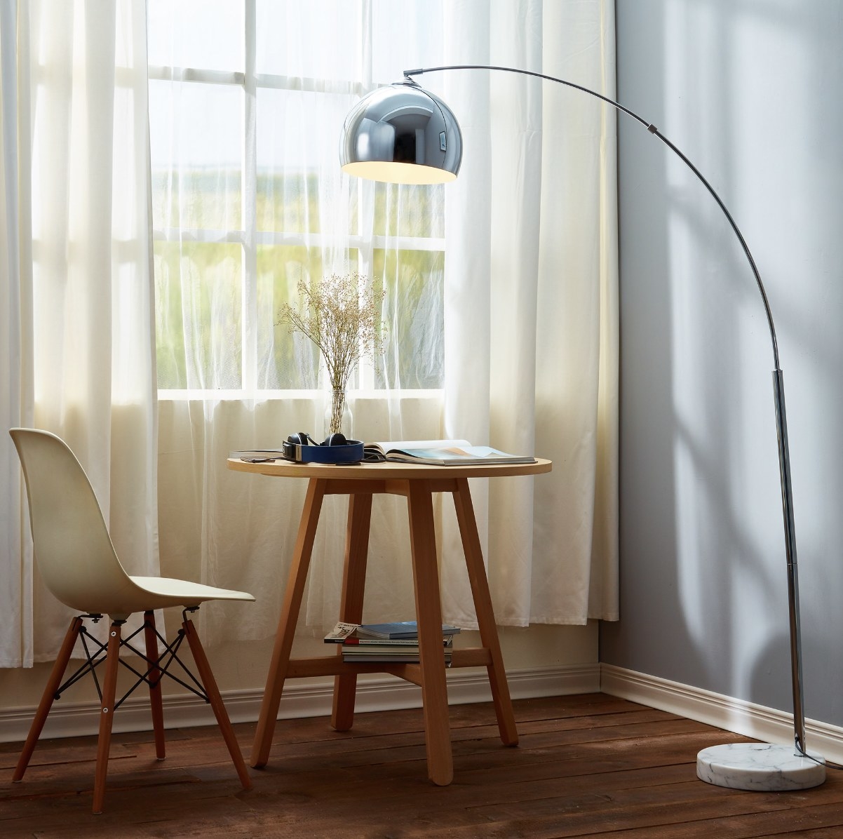A silver floor lamp by a table and chair