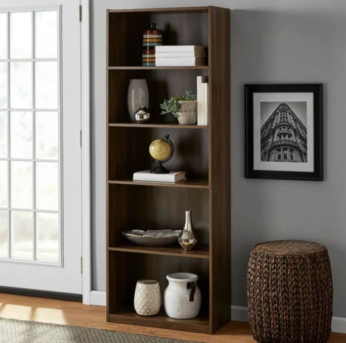 A dark brown wooden bookcase with vases and a globe on it